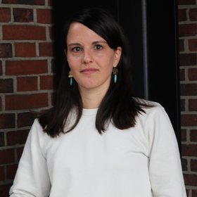 Dr. Eva Lorenz: eine Forscherin mit langen, braunen Haaren und weißem Pullover.