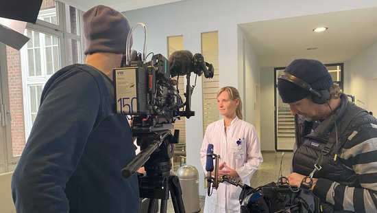 A press situation in which a doctor gives an interview in front of a camera.