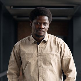 Dr Umaru Bangura: A researcher who wears short black hair and a beige shirt.