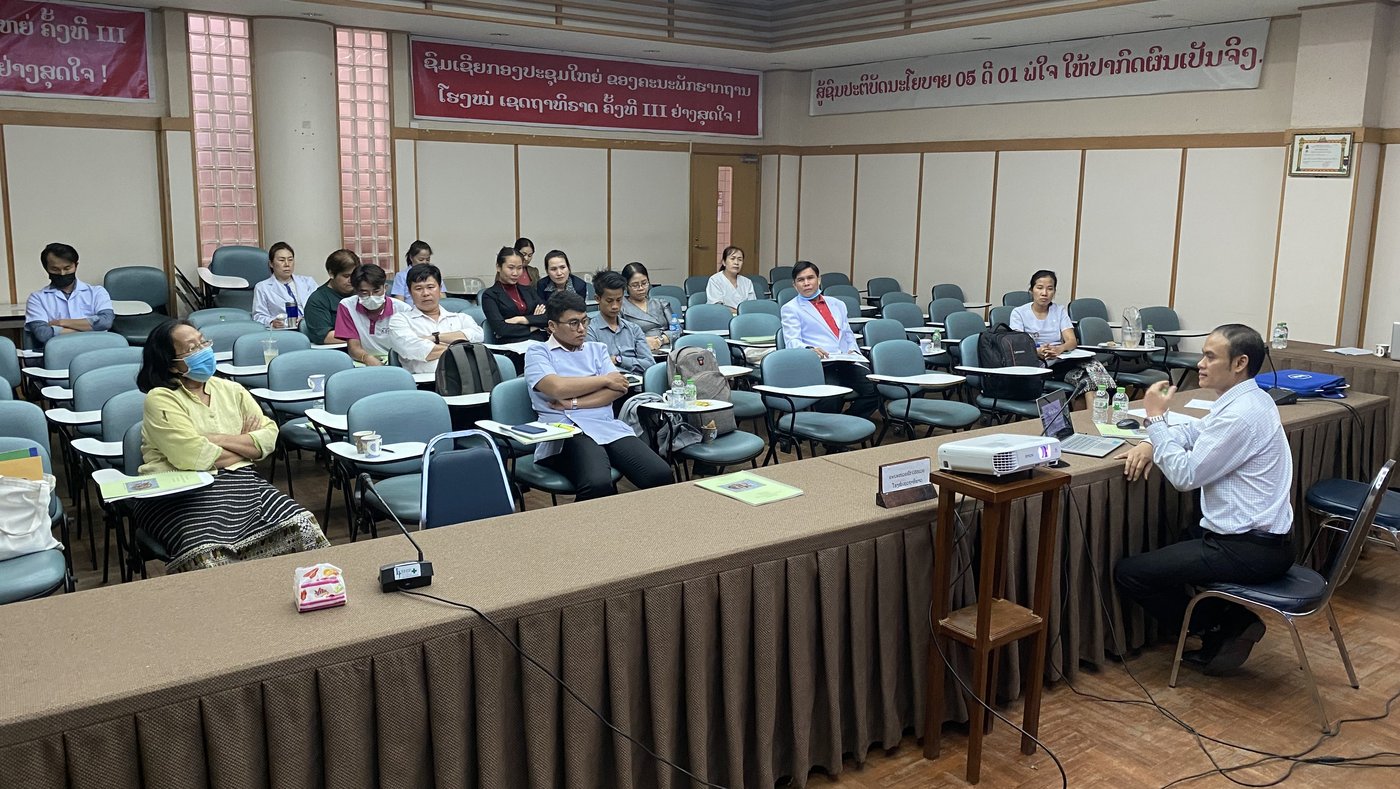 The picture shows Dr Sulaphab Hanlotxomphou (Emergency Medicine Doctor at Setthatirath Hospital) holding a lecture during the training on snakebite management in front of a group of participants.