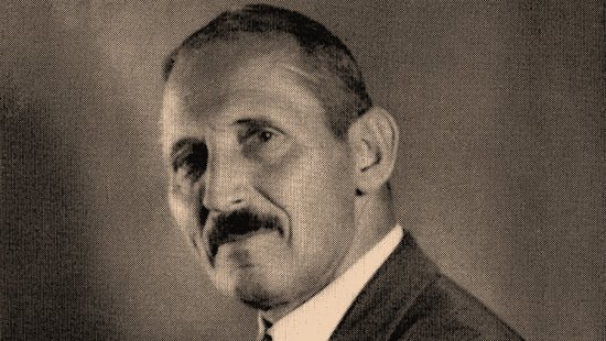 Slightly sideways black-and-white photograph of Eduard Reichenow with his arms crossed and a cigarillo in his right hand