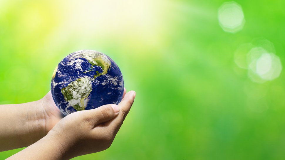 Photo of a globe in the hands of two people, against a green background.