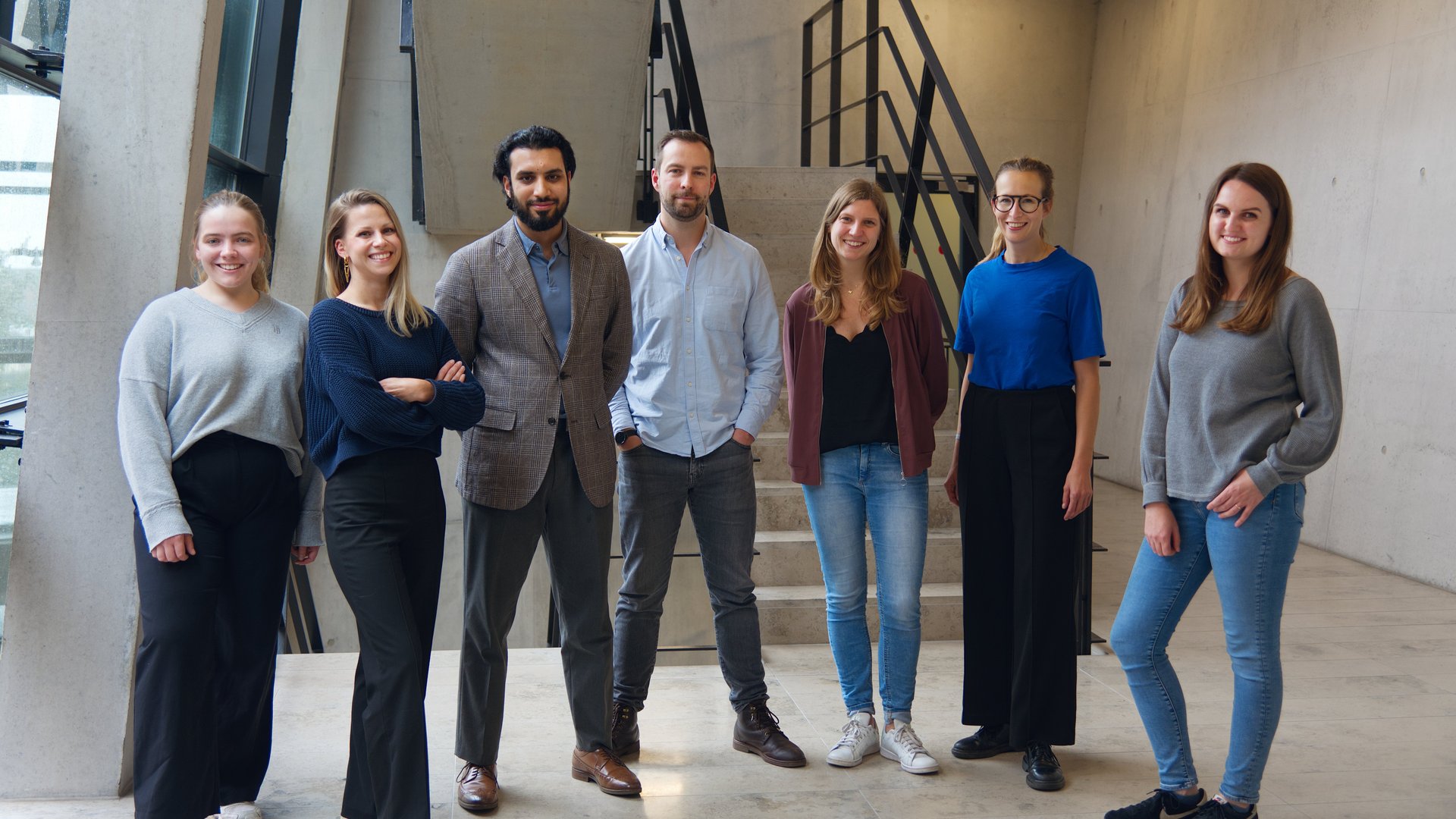 Gruppenbild der der Leibniz Research Group Lassa-Pathophysiology: 7 Personen stehen in einem Betontreppenhaus und schauen in die Kamera.
