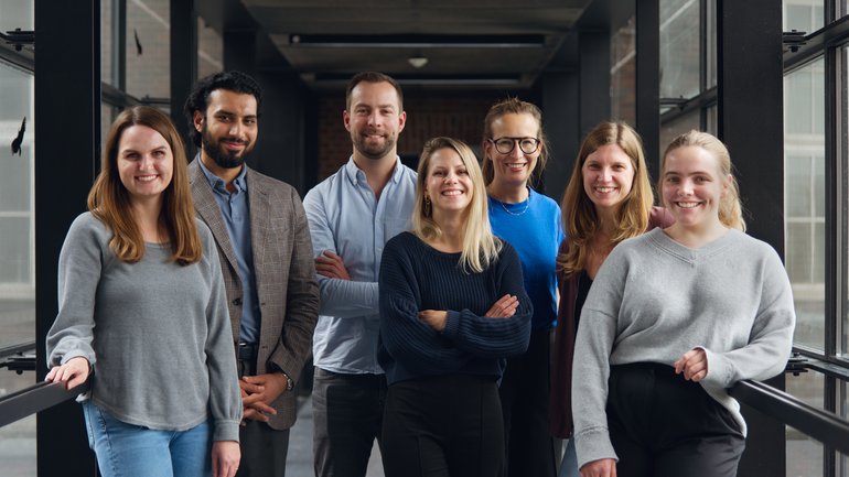 Gruppenbild der Leibniz Research Group Lassa-Pathophysiology: 7 Personen stehen in einem lichtdurchfluteten Flur und schauen in die Kamera.