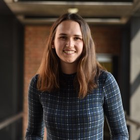 Sarah Gruninger: a researcher wearing shoulder-length hair and a black and white patterned top.