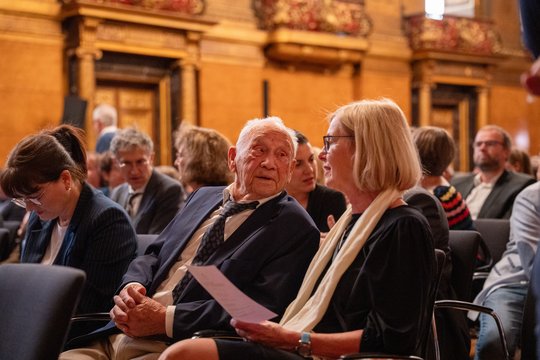 Das Foto zeigt Dr. Günther Müller 2025 beim Senatsempfang anl. des 125-jährigen Institutsjubiläums im Großen Festsaal des Hamburger Rathauses im Publikum. Neben ihm Kollegin Prof. Petra Emmerich.