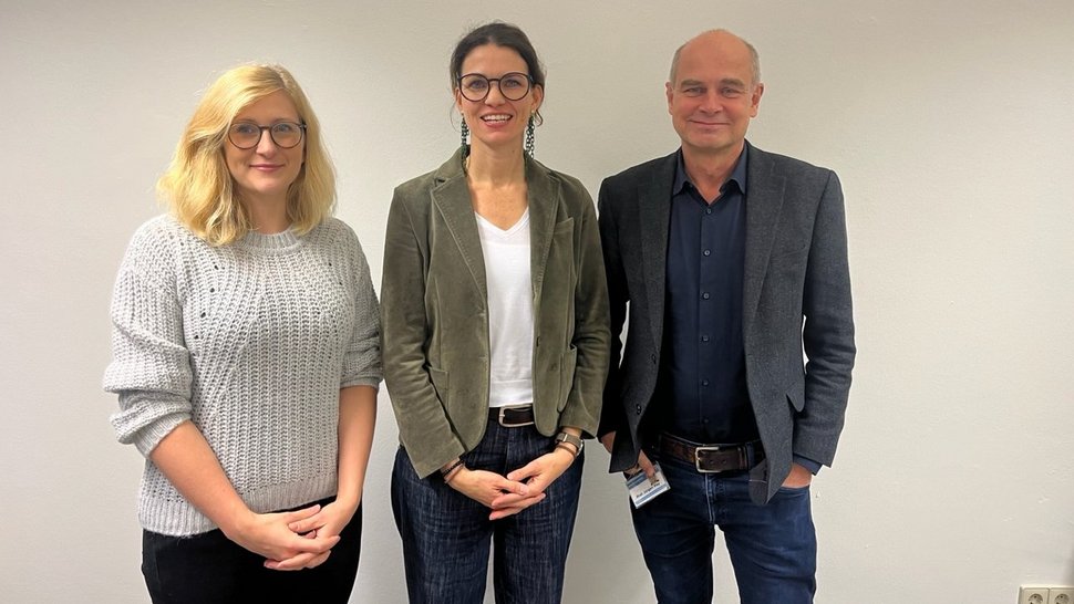 Das Foto zeigt von links nach rechts Sarah Eitze (blonde lange Haare, hellgrauer Pulli), Cornelia Betsch (dunkler Pferdeschwanz, weißes Shirt, Jeans, dunkelgrüner Blazer) und Jürgen May (Glatze, Jeans, dunkelblaues Hemd, dunkelgraues Jackett).