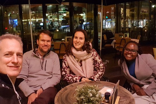 Teammitglieder aus Nijmegen und Hamburg Das Foto zeigt zwei Forscherinnen und zwei Forscher an einem Restauranttisch sitzen und lächeln.