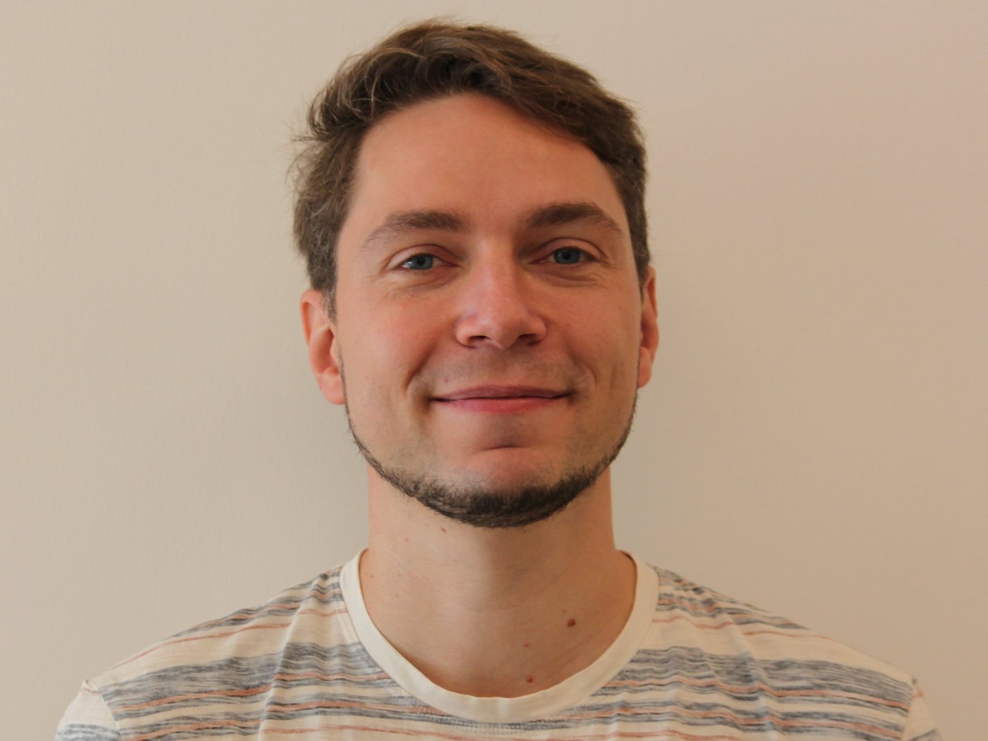 Dr. Joachim Matz Dr. Joachim Matz: ein Forscher, der in die Kamera lächelt. Er trägt ein gestreiftes Shirt, einen Bart an Kinn und Hals und kurzes braunes Haar.