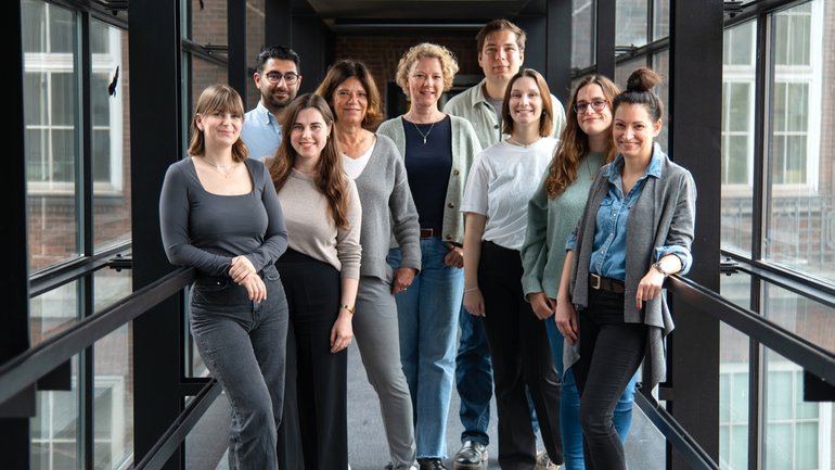 In the picture, the 9 members of the working group are standing in the glass corridor from the old building to the new building of the Bernhard Nocht Institute for Tropical Medicine and smiling into the camera.
