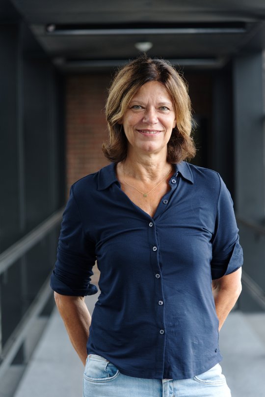 Das Portraitfoto zeigt eine Forscherin mit halblangen braunen Haaren, sie trägt eine dunkelblaue Bluse.