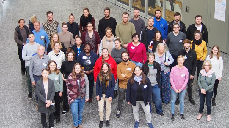 Retreat 2023 Eine Gruppe von Mitarbeitern der Abteilung Virologie hat sich im Foyer für ein Gruppenfoto versammelt.