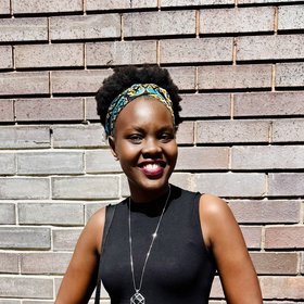 A smiling woman in front of a brick wall