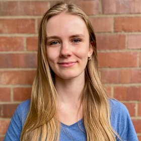 Selina Krüger: A doctoral student smiles at the camera. She wears her long blond hair loose and a blue shirt.