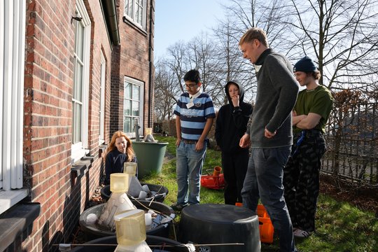 Auf dem Foto ist eine Gruppe mit drei Schüler:innen und zwei Forschenden im Garten bei Mückenfallen zu sehen.