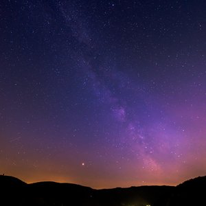 Das Foto zeigt einen städtischen Nachthimmel mit starker Lichtverschmutzung über den umgebenden Bergen.