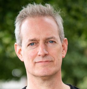 Dr. Tobias Spielmann: ein Forscher mit kurzen, grauen Haaren und einem Dreitagebart, der ein dunkles Oberteil trägt.