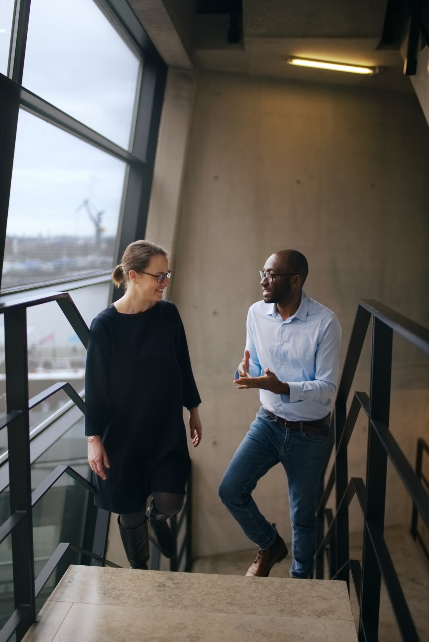 Two friendly people talking while walking on a staircase.