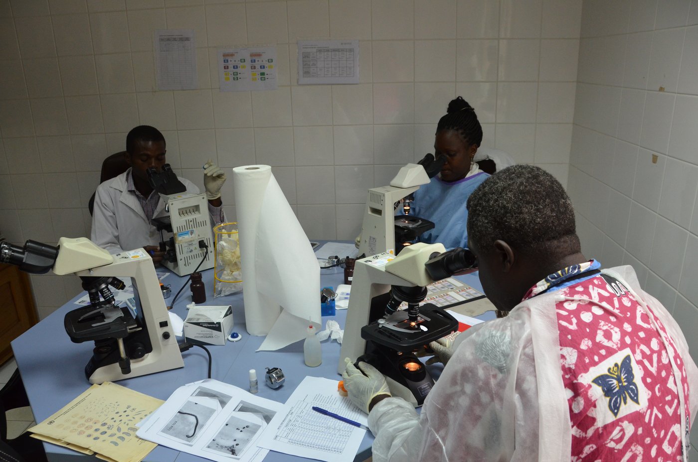 Three scientist are working on a round laboratory desk.