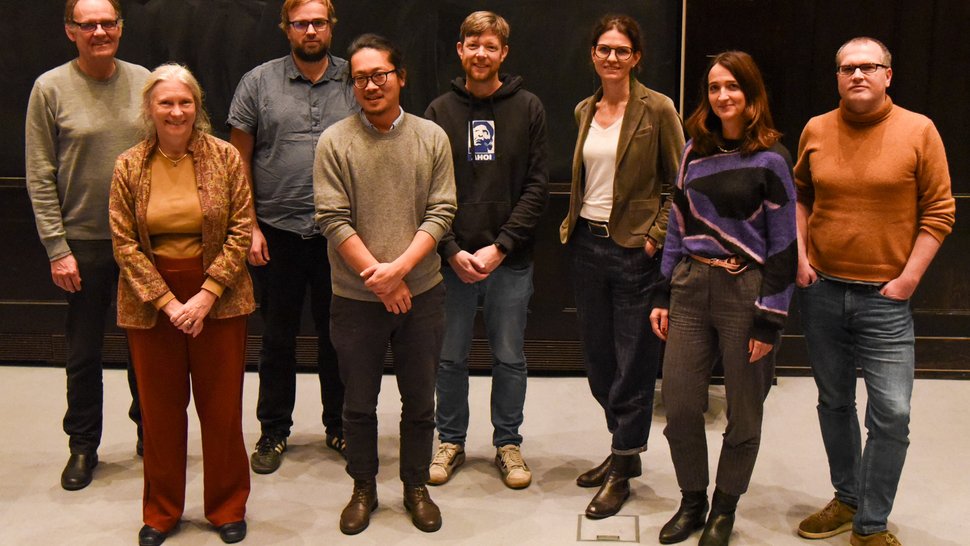 The photo shows ten researchers standing in front of a screen in the lecture hall.