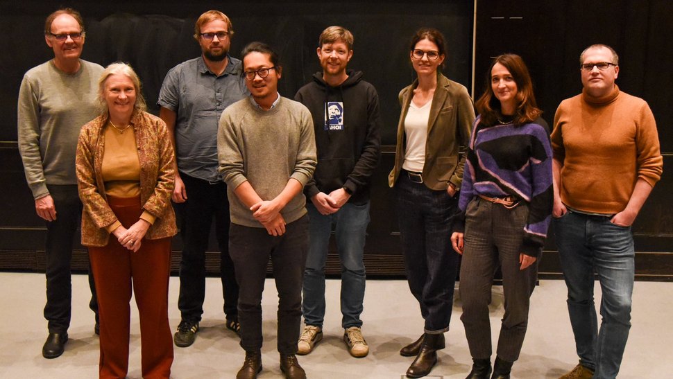 Die Gruppenleitungen der Sektion Implementation. Es fehlen John Amuasi und Ghyslain Mombo-Ngoma. Das Foto zeigt zehn Forscherinnen und Forscher vor einer Leinwand im Hörsaal stehen.