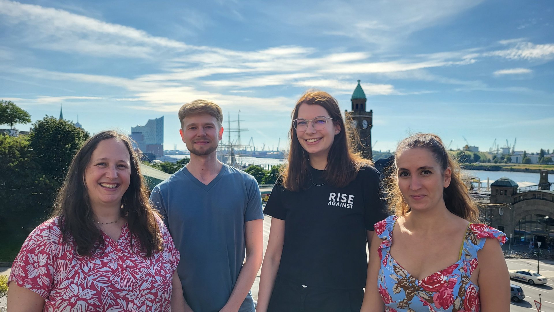 Gruppenfoto Laborgruppe Escudero-Pérez: 4 Personen stehen draußen vor blauem, mit leichten Schleierwolken bedecktem Himmel und tragen sommerliche Kleidung.