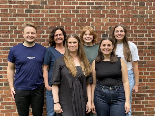 Laborgruppe Bachmann: eine Grupe von Forscher:innen steht draußen und lacht in die Kamera.