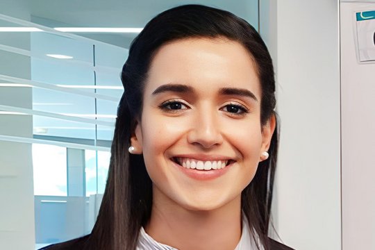 A friendly female scientist with long dark hair smiles into the camera