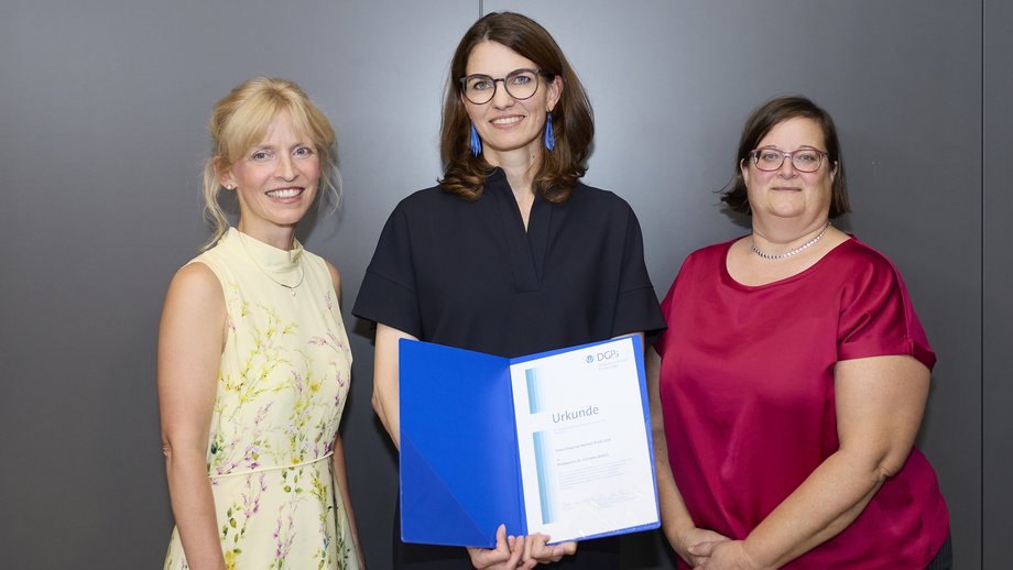 The photo shows three women; in the middle is Cornelia Betsch holding the certificate.