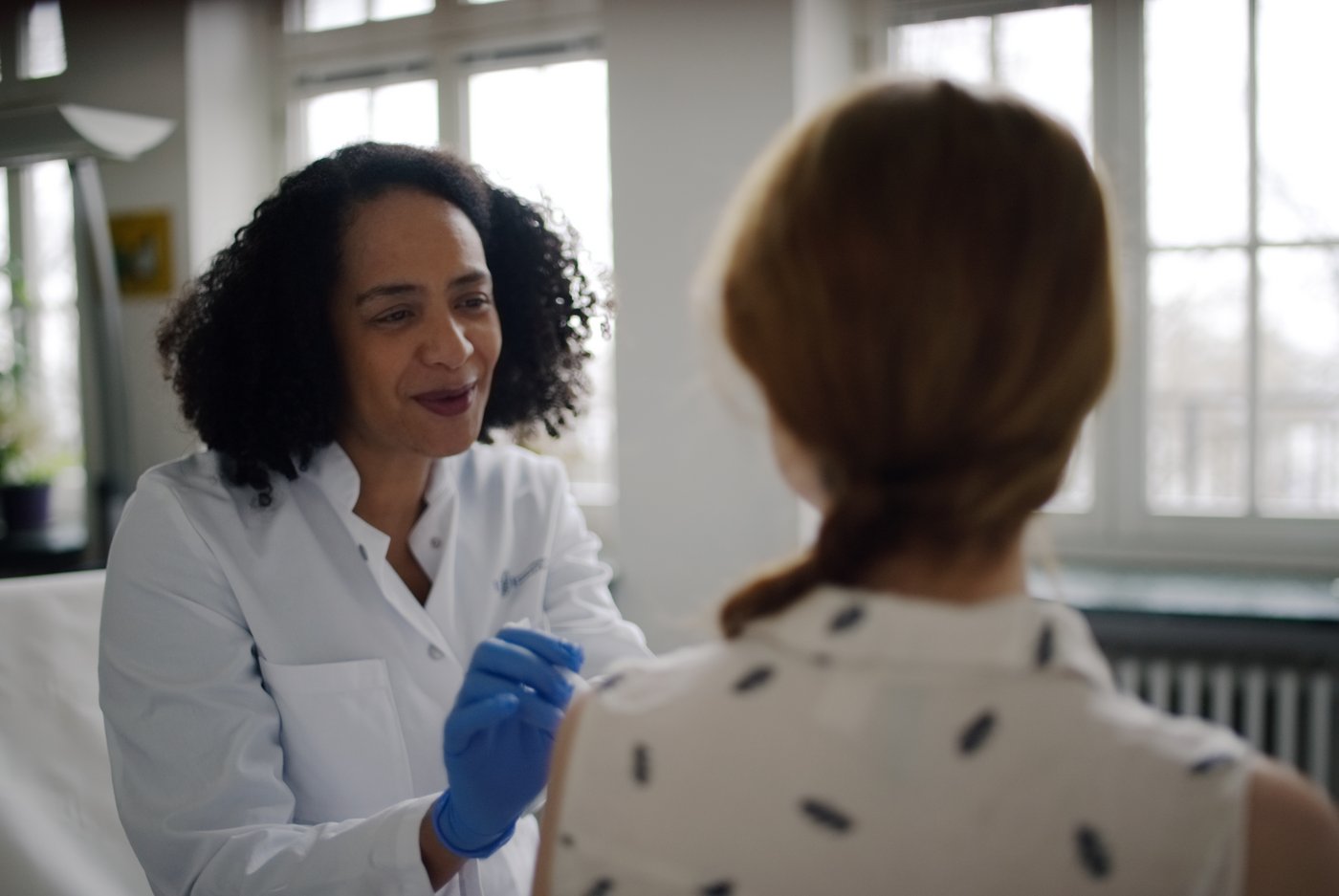 A doctor advises a patient, whom we look over her shoulder from behind.