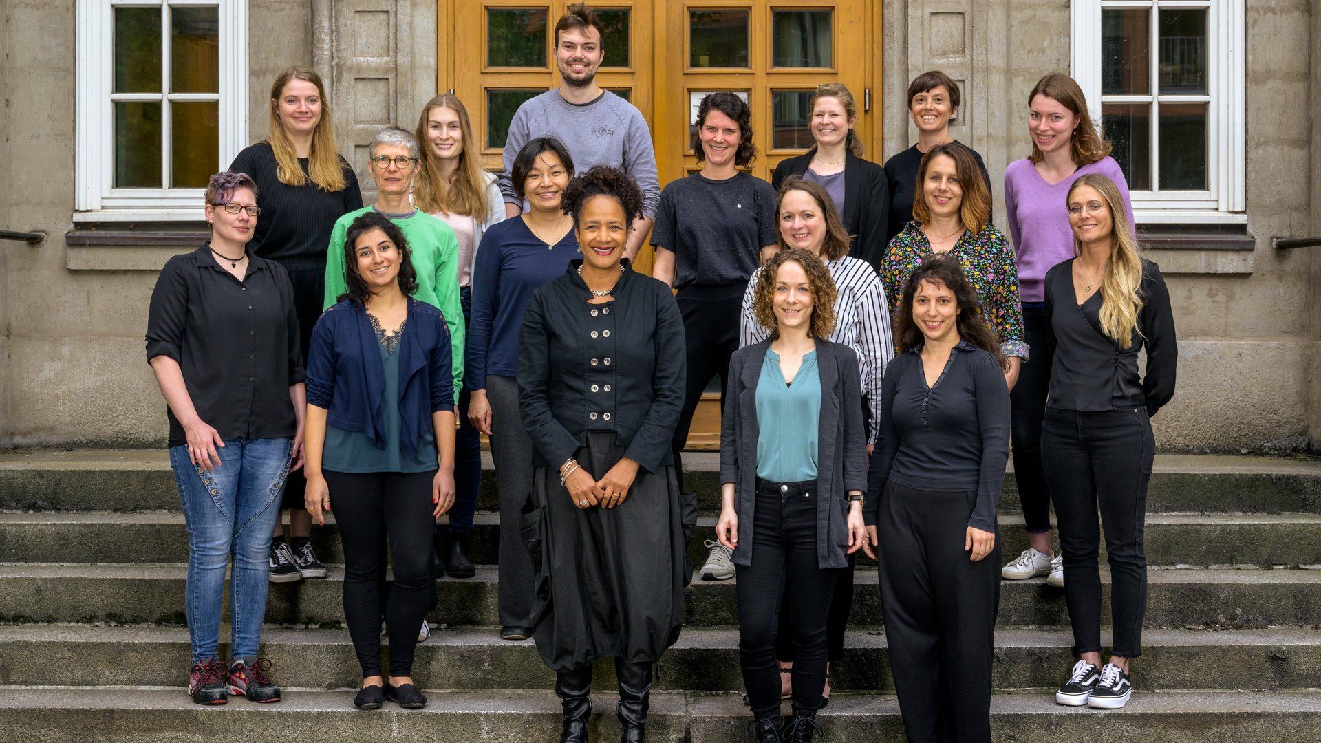 Diverse group of researchers standing on a staircase which leads to the old building of BNITM