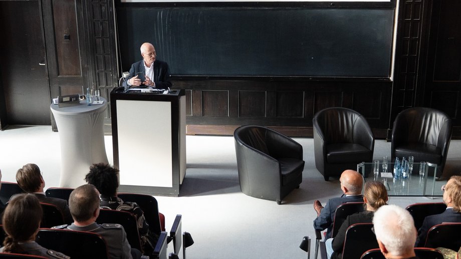 Foto des Ersten Bürgermeisters Dr. Peter Tschentscher am Redepult im historischen Hörsaal des BNITM. Im Vordergrun dicht besetzte Sitzreihen.