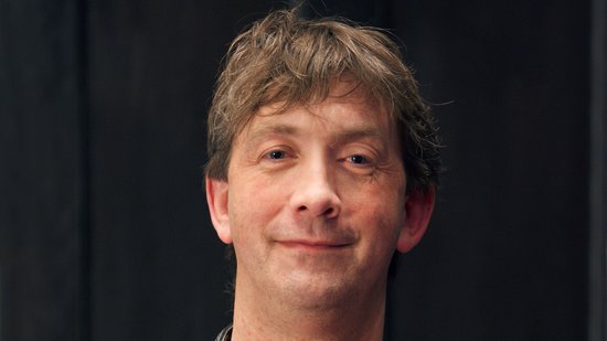 Porträtfoto von Dr. Thorsten Thye: kurze dunkle fransige Haare, braunes Poloshort, verschränkte Arme. Er blickt freundlich in die Kamera.