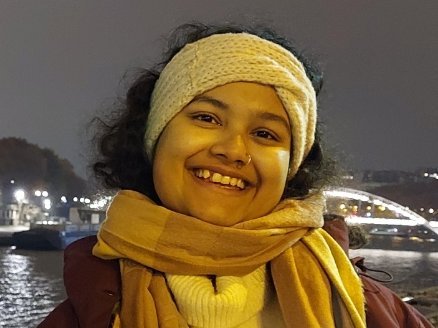 Moumita Sengupta Eine junge Frau lehnt an einer Brücke und lächelt in die Kamera