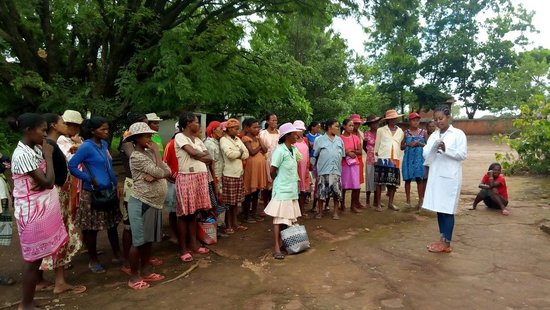 Eine große Gruppe schwangerer Frauen steht vor einer Pflegerin, die anhand eines Zettels der Gruppe etwas erklärt. Die Gruppe steht draußen im Grünen.