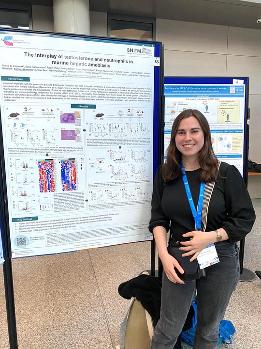 Barbara Honecker from RG Lotter stands in front of her poster at the conference, smiles into the camera and waits for interested visitors