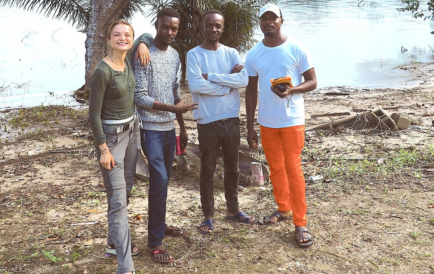 The team on site A mixed group of people are standing by a calm body of water, chatting amiably.