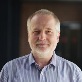Prof. Dr. Stephan Günther: ein Forscher, der kurzes, graues Haar, einen kürzeren Bart und ein blaues Hemd trägt.