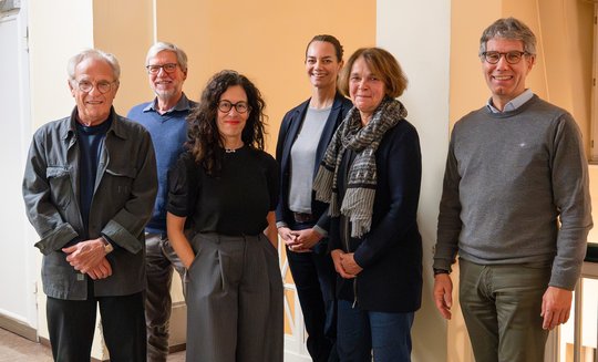 Mehrere Forscher:innen unterschiedlichen Alters und Geschlechts die in der Gruppe stehen freundlich Richtung Kamera schauen.