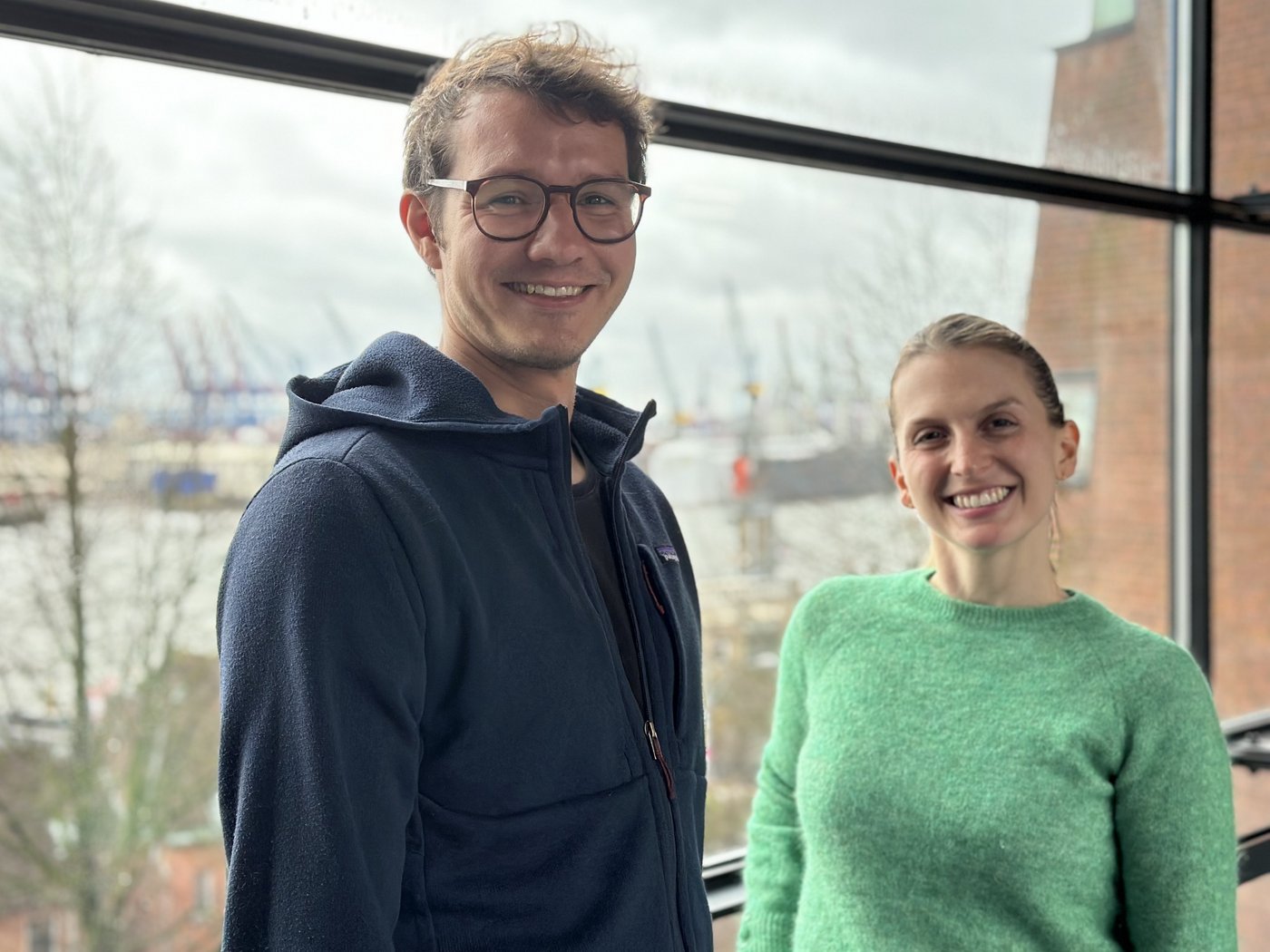 The picture shows two researchers, a man and a woman, both smiling friendly into the camera.