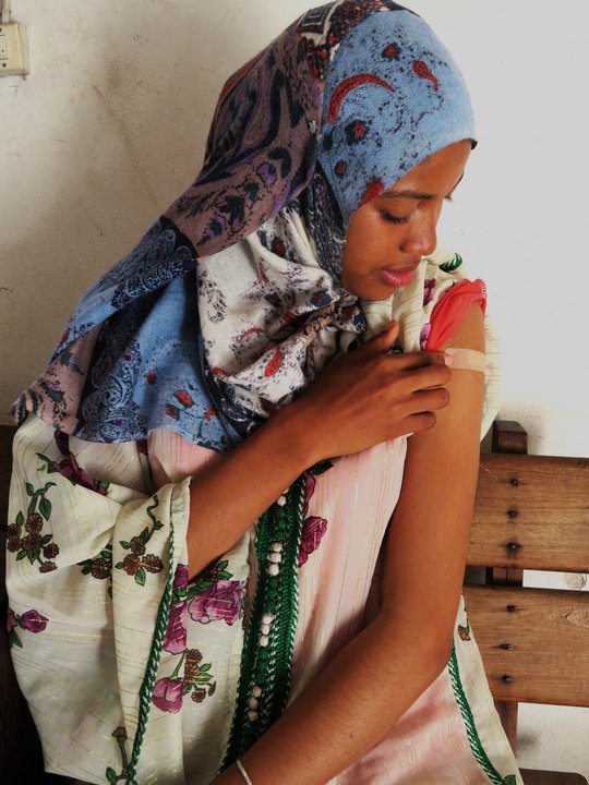 Sitting women after Vaccination point on the vacination area on her arm
