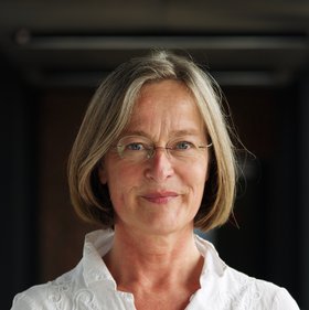 Levke Harring: a woman in white blouse with blond bob and rimless glasses.