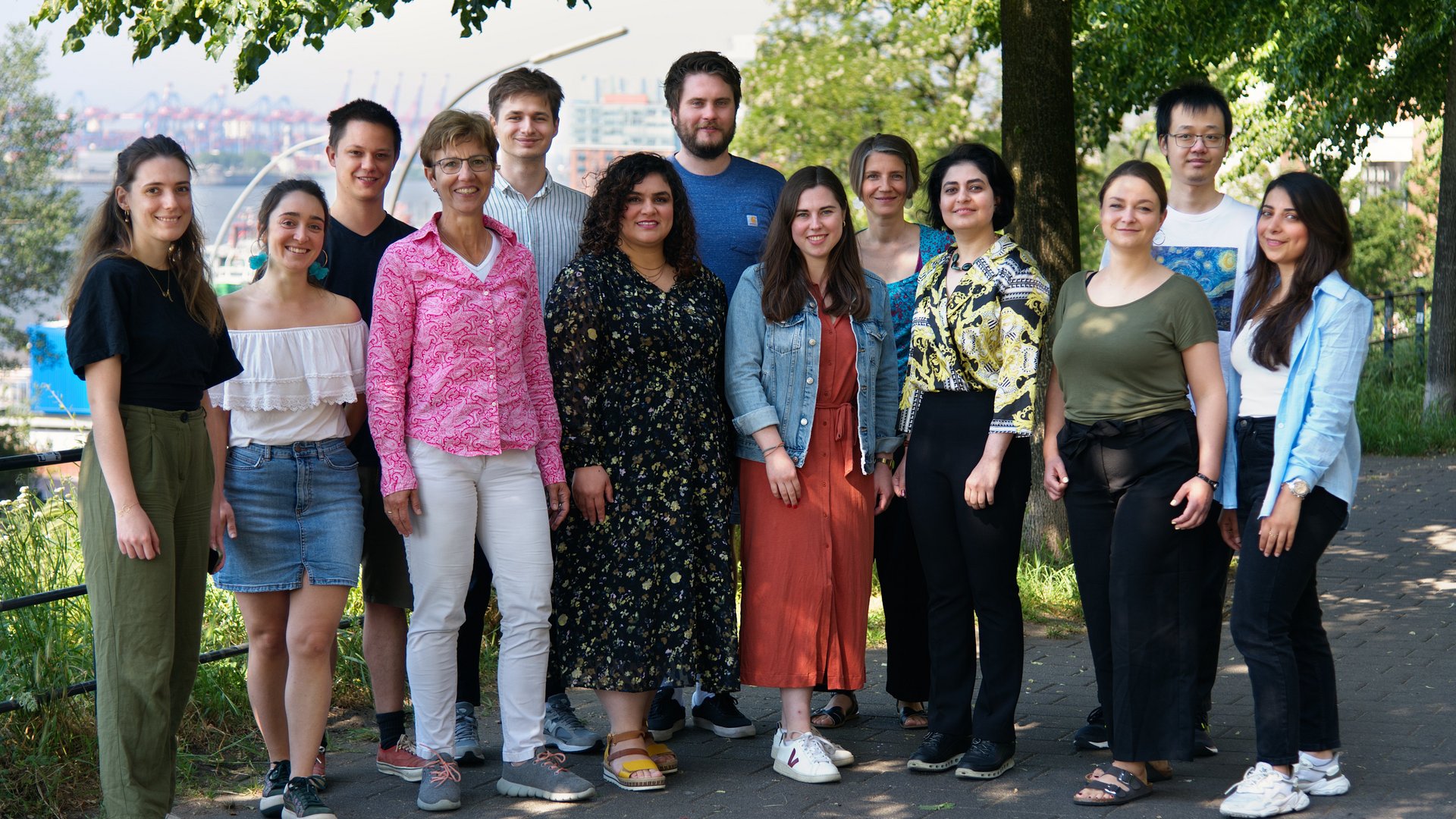 Photo of a group of diverse researchers standing on a pathway under a tree