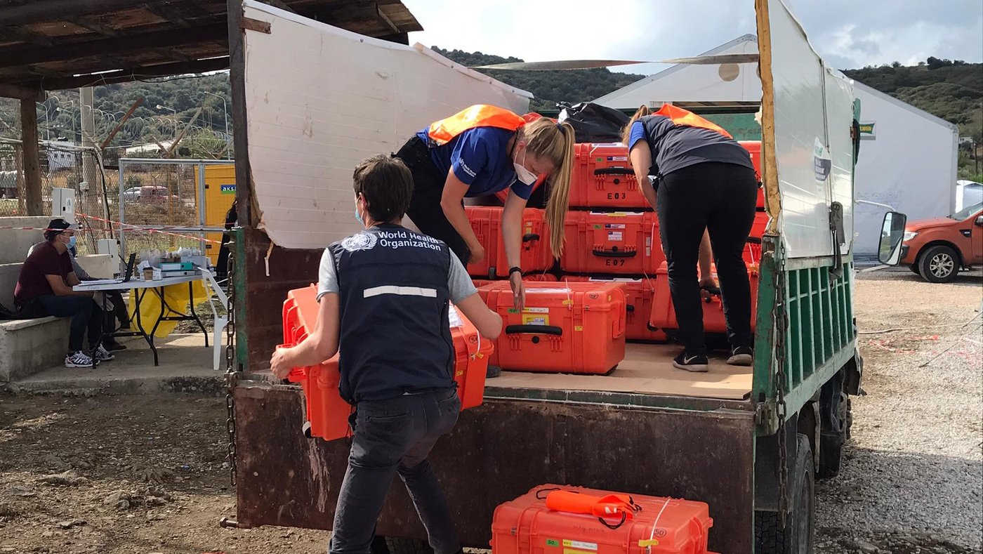 Offloading of EMLab boxes from a truck at the site of operations. Three EMLab experts unload a unit as it is delivered to the site of operations for an emergency response to COVID-19.