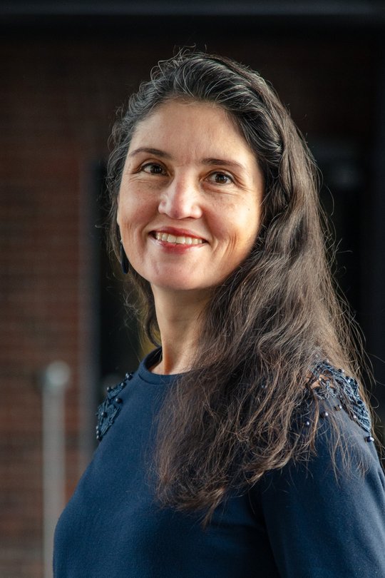 Das Foto zeigt Dr. Andrea Molina Alvarado, eine Forscherin mit langen dunklen Haaren und dunkelblauem Pullover. Sie schaut freundlich in die Kamera.