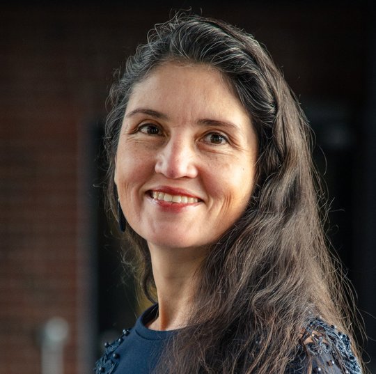 Das Foto zeigt Dr. Andrea Molina Alvarado, eine Forscherin mit langen dunklen Haaren und dunkelblauem Pullover. Sie schaut freundlich in die Kamera.