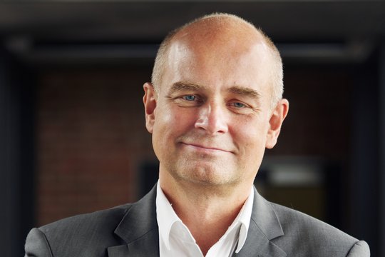 Prof. Dr. Jürgen May:ein Forscher, der eine Glatze hat und ein weißes Hemd mit grauem Sakko trägt.