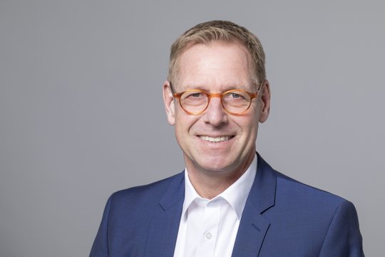 Prof. Dr. Christian Gerloff Das Foto zeigt einen blonden Herren, Herrn Prof. Crhistian Gerloff, mit kurzen Haaren und einer Hornbrille. Er trägt ein weißes Hemd und ein blaues Jacket.