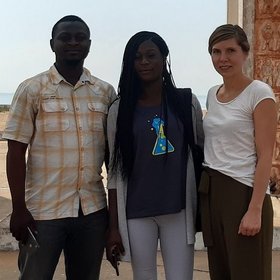 Dr Hanna Jöst: A total of three people can be seen. On the far right is Dr Hanna Jöst, wearing her brown hair in a braid, a white shirt and black, long and loose pants.