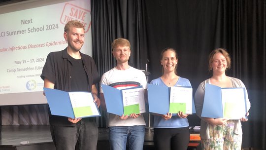 The photo shows two young men and two young women holding certificates.